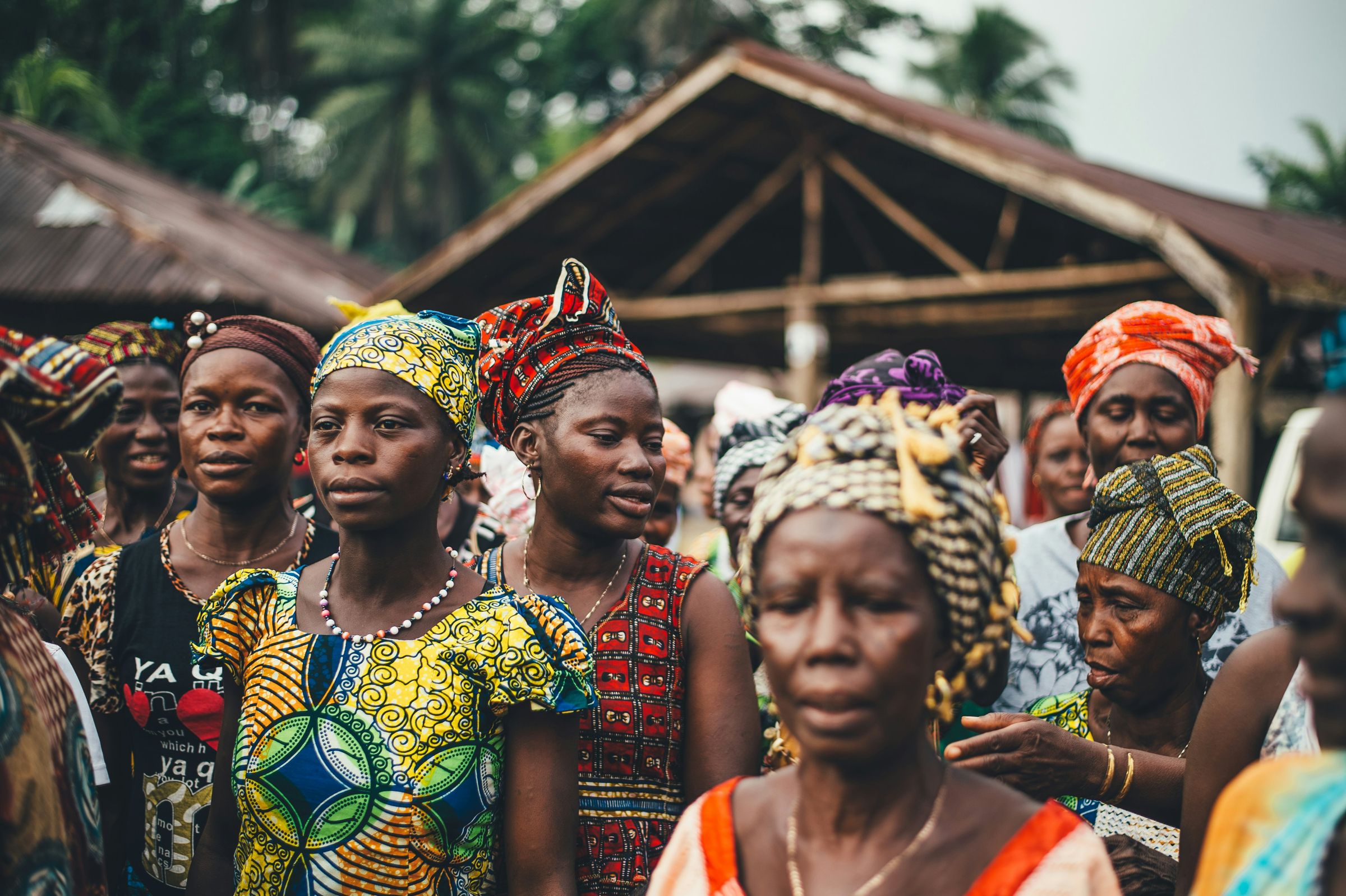 A crowd of women in colourful patterned clothing and headwraps at a community gathering.